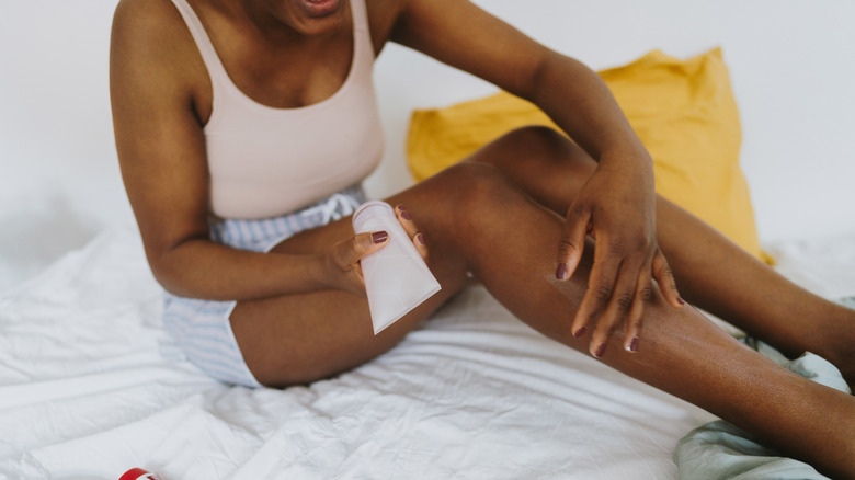 Woman applying moisturizer.