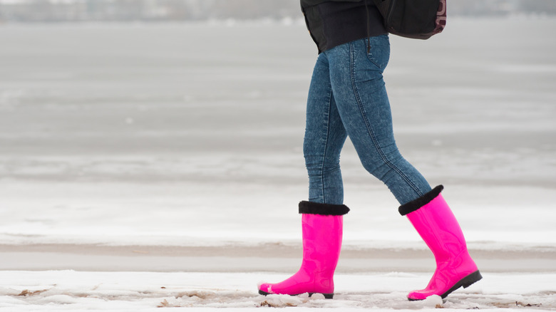 Woman walks on snow in rubber boots