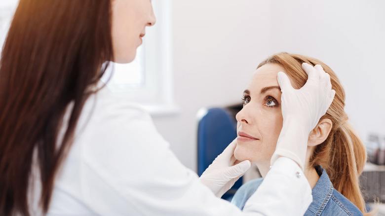 doctor examining woman's face