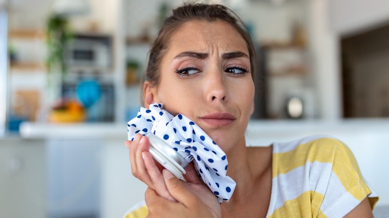 Woman holding ice pack to face