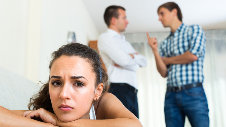 men arguing behind woman