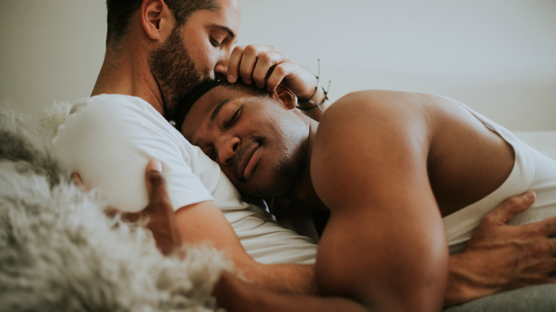 Gay couple cuddling in bed