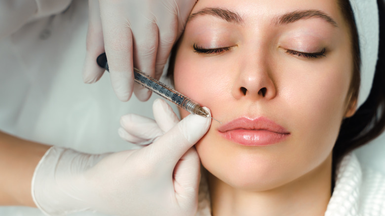 Injectionist's hands placing syringe near patient's lips