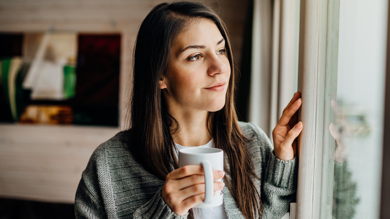 woman holding mug by window