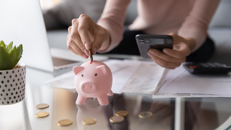 Woman putting money in her piggy bank