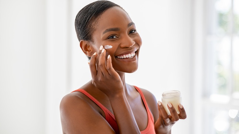 Woman applying moisturizer to her face