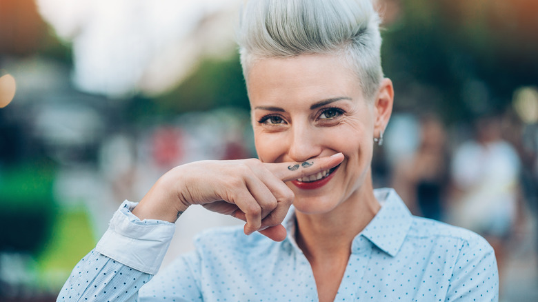 Woman holds up finger tattoo