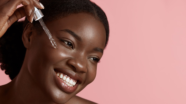 woman putting on facial serum with a dropper