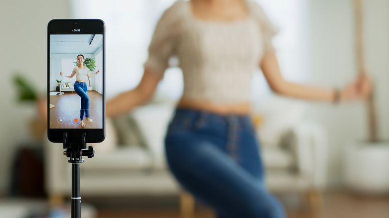 Woman recording herself using phone on tripod