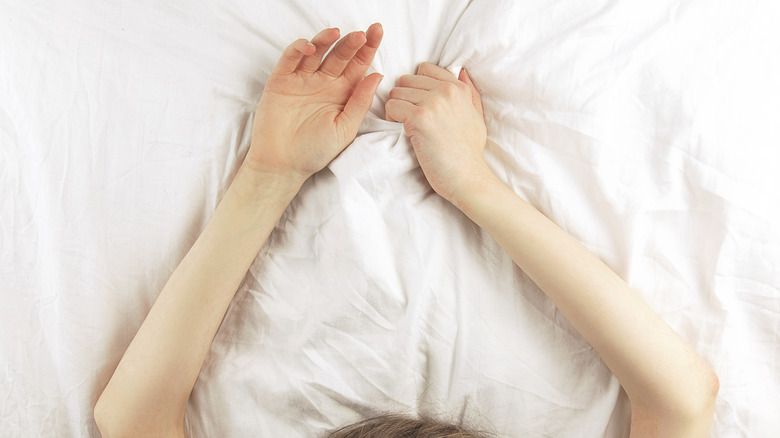 Woman clenching sheets