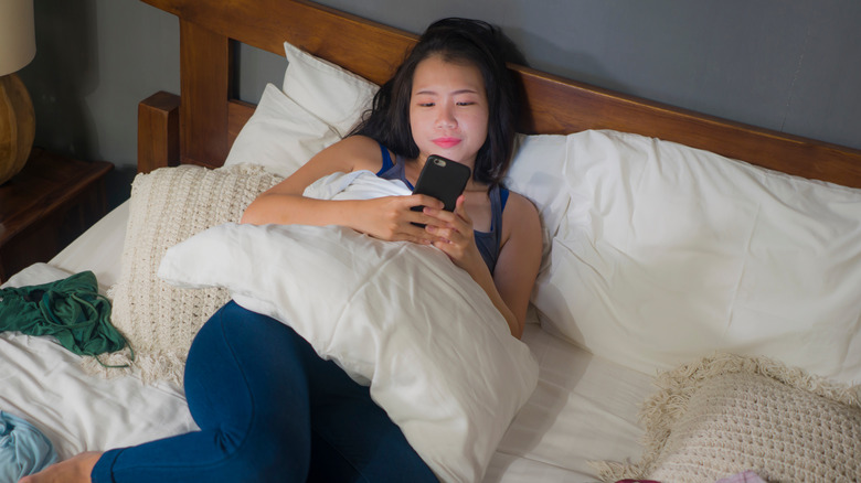 Woman looking at her phone surrounded by clothes