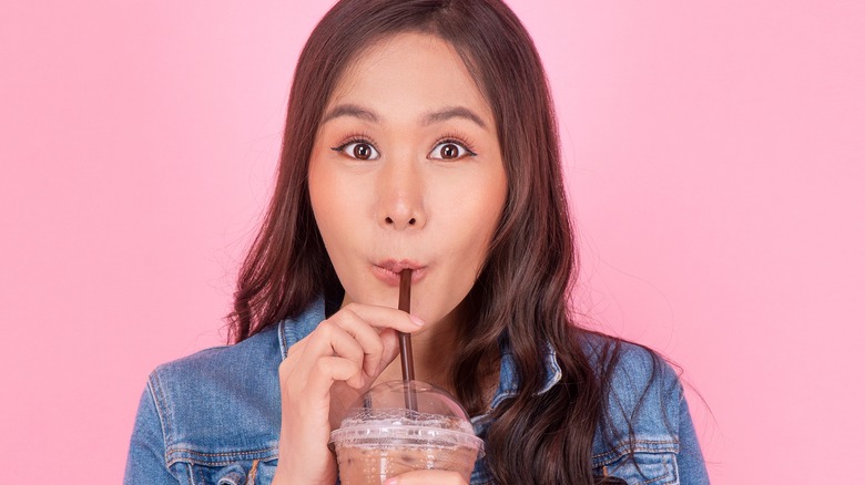 Model drinking iced coffee through straw