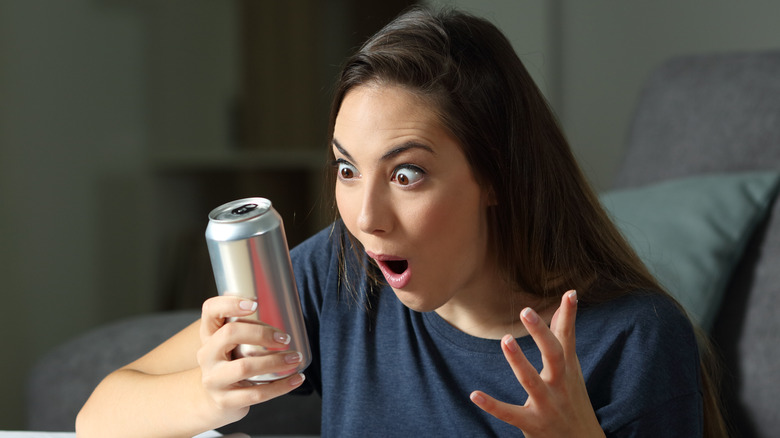 Model looking at drink can with shocked expression