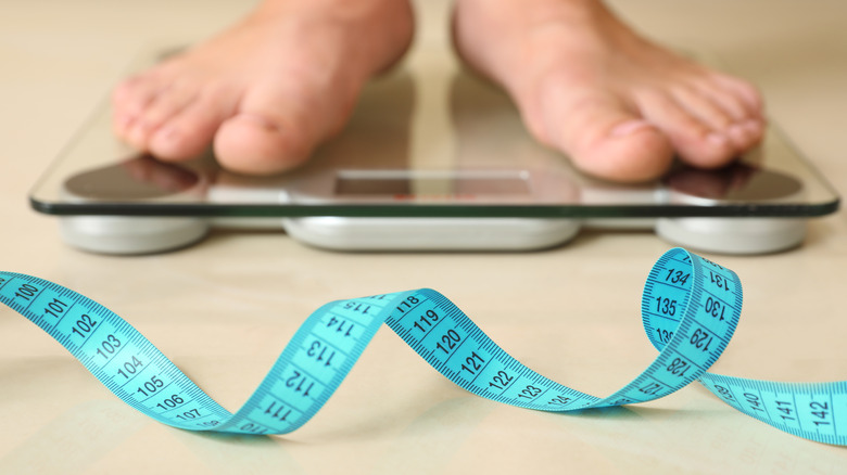 Person standing on scale with tape measure