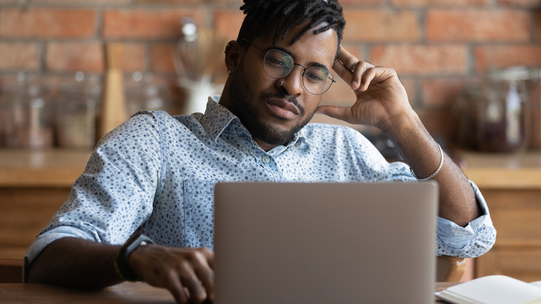 Bemused Black man looking at laptop