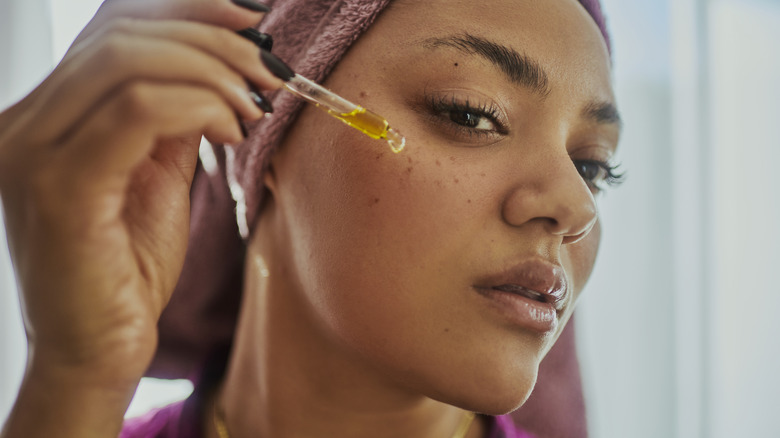 woman applying oil to her face