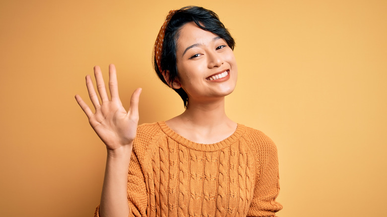 Woman holding up the number five