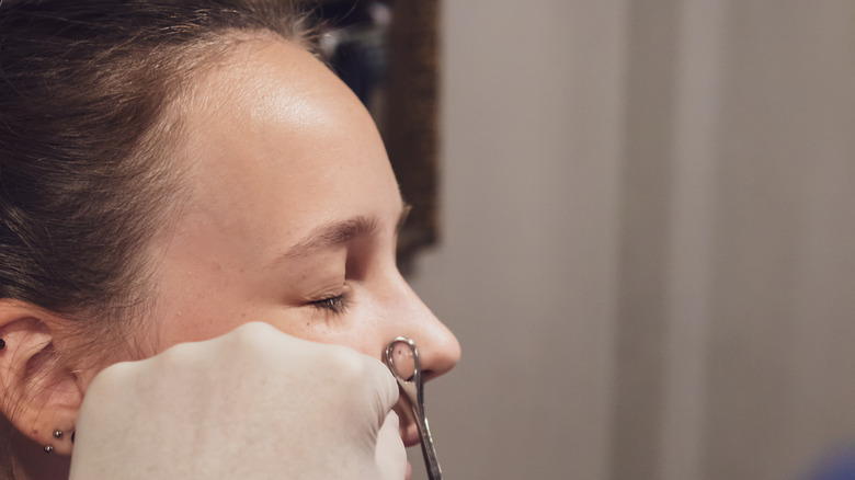 Woman getting nose piercing 