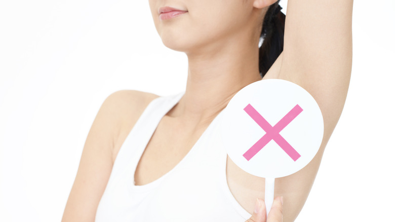 Woman holding 'x' sign over armpit