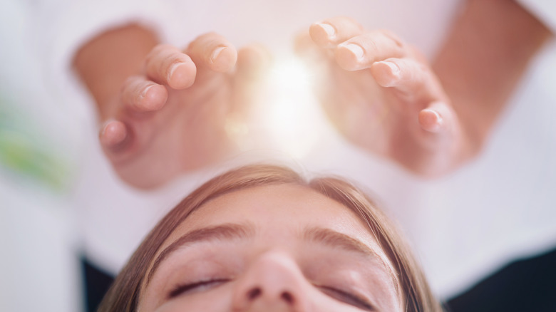 woman receiving reiki around head or crown chakra