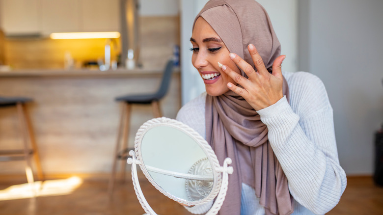 hijabi woman applying face cream