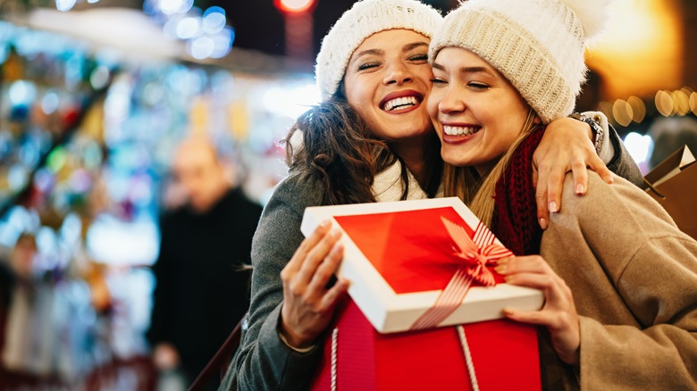 Two women holding red gift box