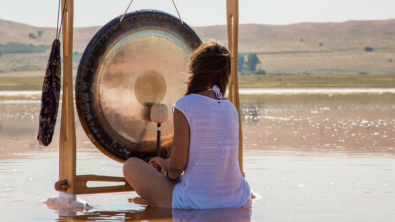 Woman ringing gong in lake