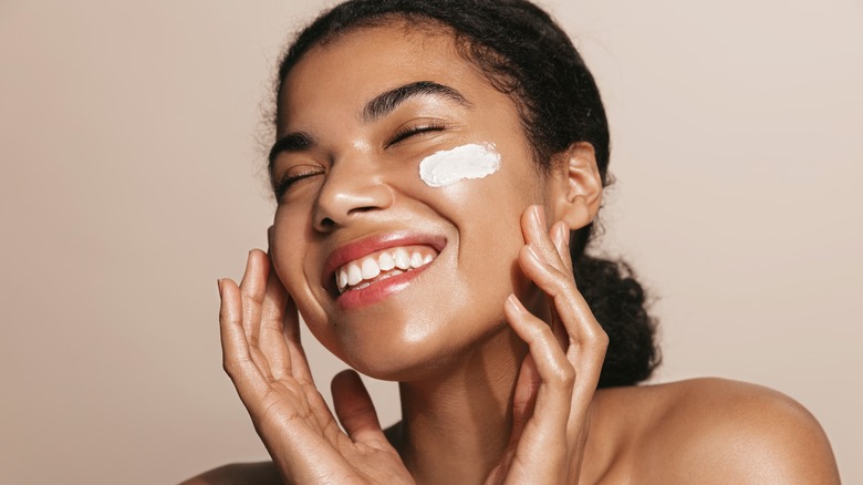 Woman applying skincare product onto face