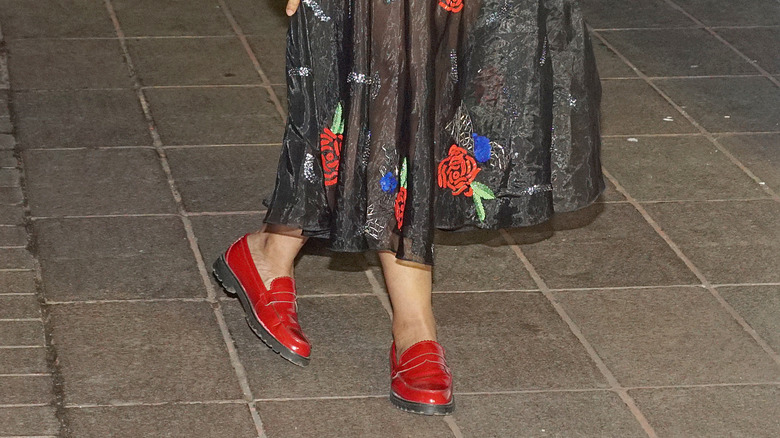 A woman wearing red loafers