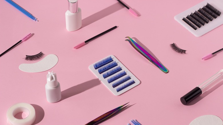 different eyelash tools on pink background