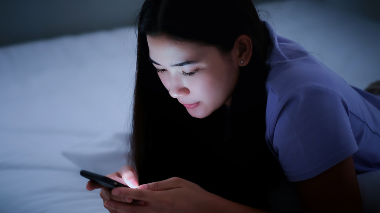 Asian girl using phone in bed