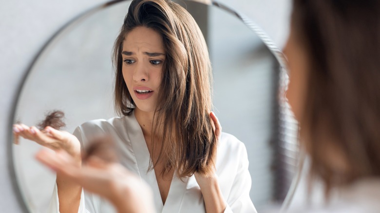 woman holding shedded hair in hand