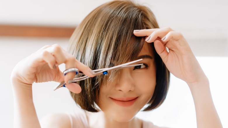 woman dry cutting hair with scissors