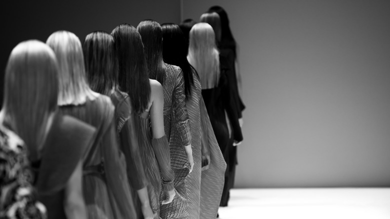 Models walking down runway.