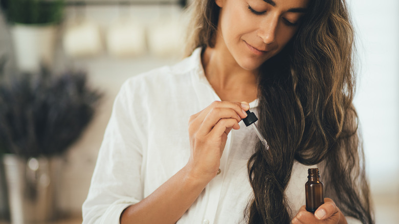 Woman applying oil onto hair