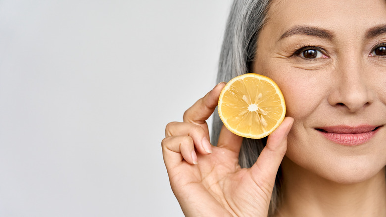 closeup of half a woman's face holding up half a lemon