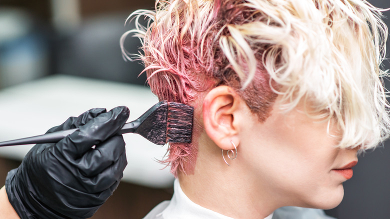 Hair stylist dyeing hair pink