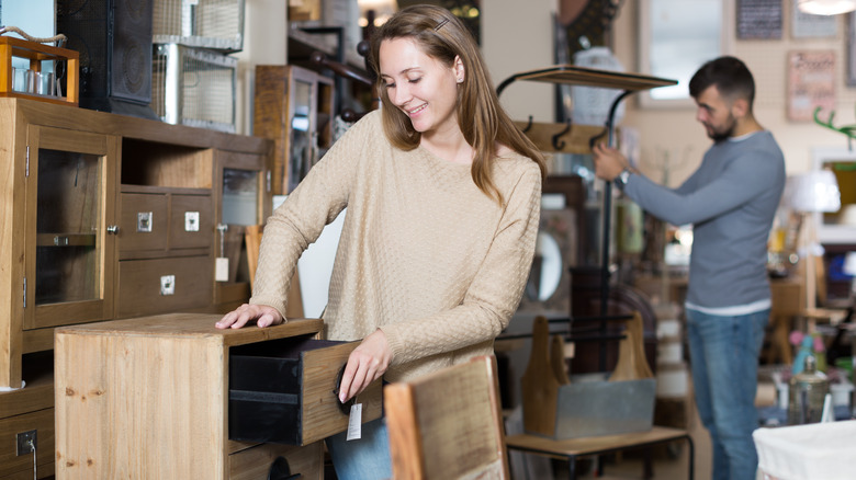 Two people examine secondhand furniture in a shop