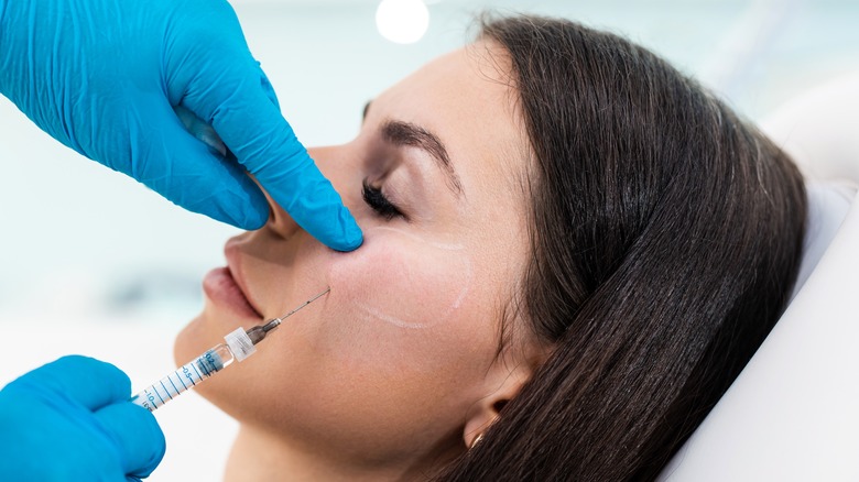 doctor injecting filler into woman's cheek