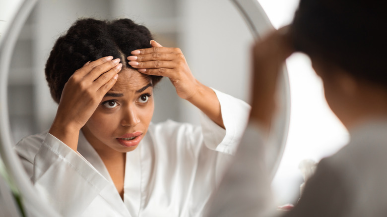 woman analyzing hair in mirror