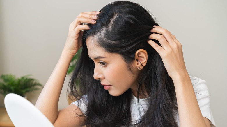 woman looking at scalp in mirror