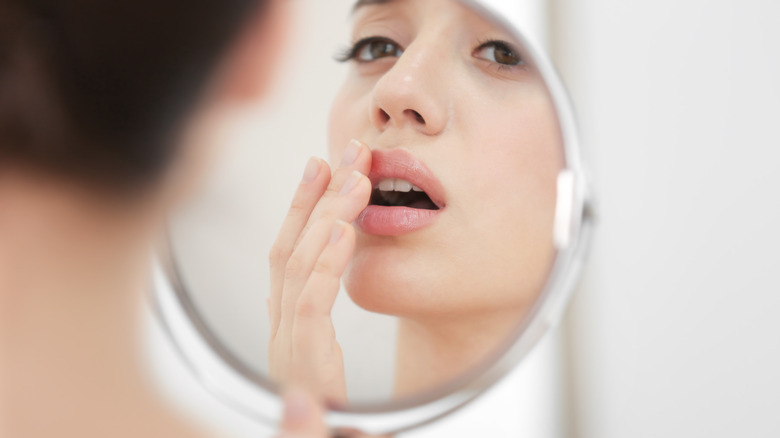 woman looking in mirror at cold sore