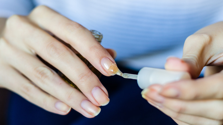 person applying nail hardener to nails