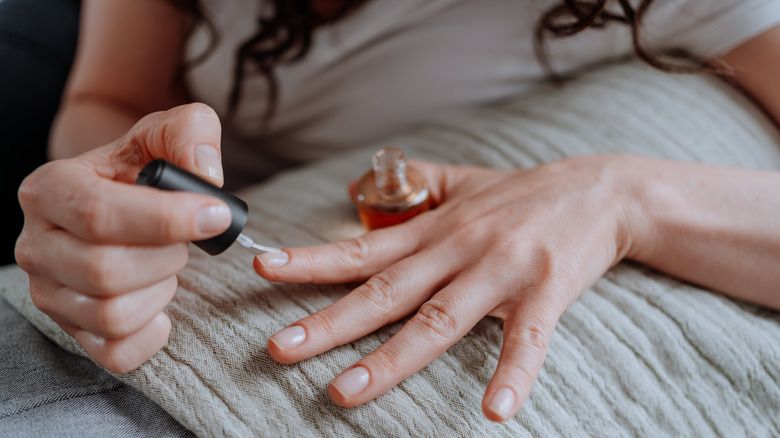 woman applying nail hardener to nails