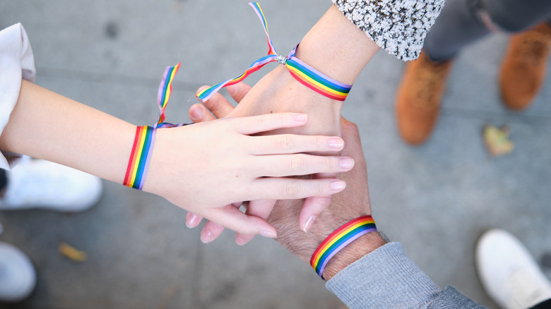 Three hands with rainbow bracelets