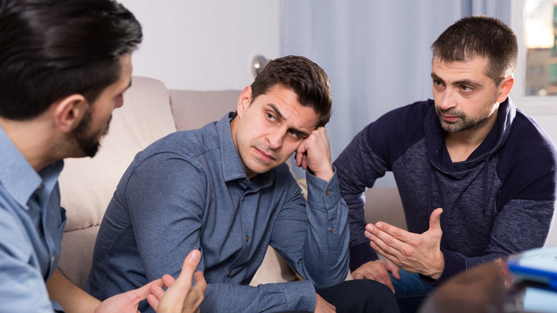 Three men talking on couch