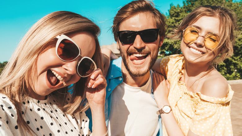 Three people smiling in sunglasses