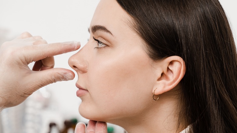 doctor examining woman's nose