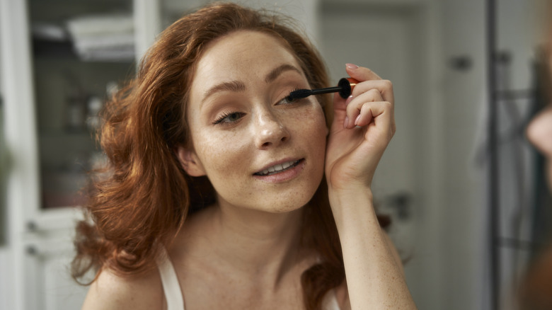 Woman putting on mascara