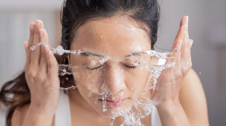 woman splashing water on face 